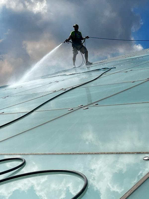 Worker pressure washing glass roof of Sarasota National Cemetery amphitheater